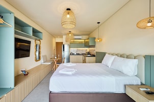 Une chambre d’hôtel moderne dotée d’un grand lit, d’une petite kitchenette, d’un coin repas et d’un téléviseur.