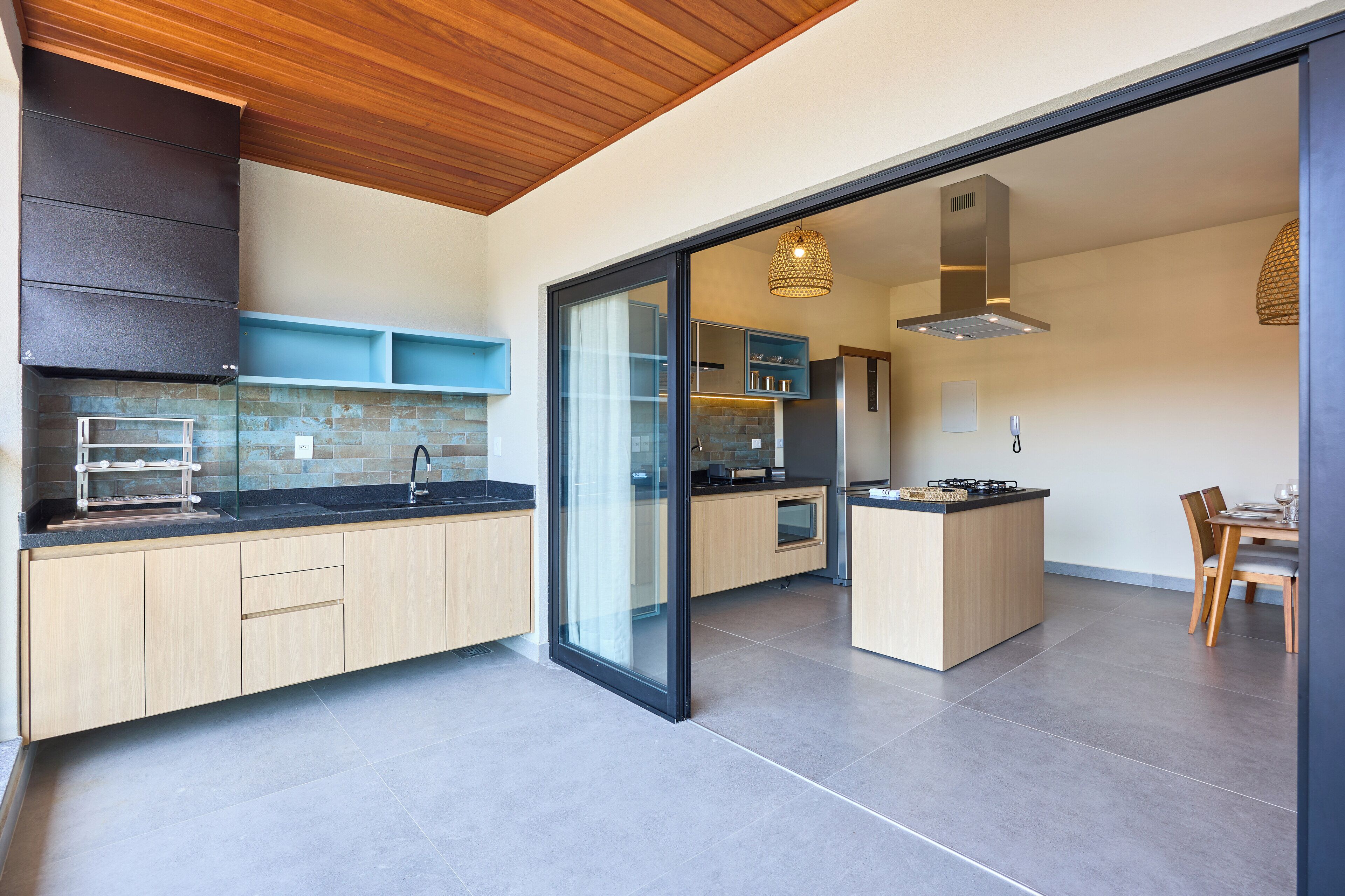 Una cocina moderna con una isla central, armarios de madera y un ventanal que da a un comedor.