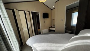 Une chambre d’hôtel avec un grand lit, une télévision, un miroir et une armoire.