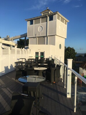 Eine Dachterrasse mit Sitzgelegenheiten im Freien und einem kleinen Turm.