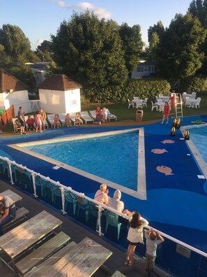 A swimming pool with lounge chairs and a small building in the background.