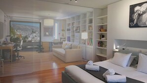 Quarto de hotel moderno com uma cama grande, uma mesa, um sofá e uma estante de livros.