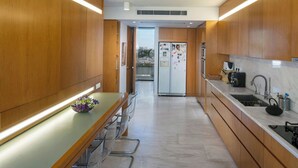 Cozinha moderna com armários de madeira, bancada de mármore e geladeira de aço inoxidável.