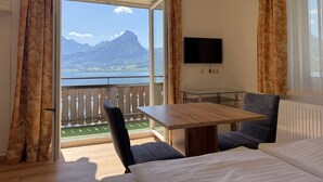 Habitación de hotel con balcón, cama, mesa y televisor.