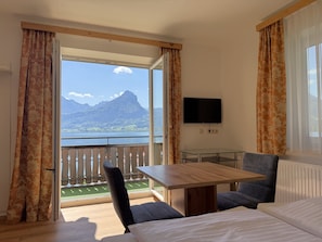 Habitación de hotel con balcón, cama, mesa y televisor.