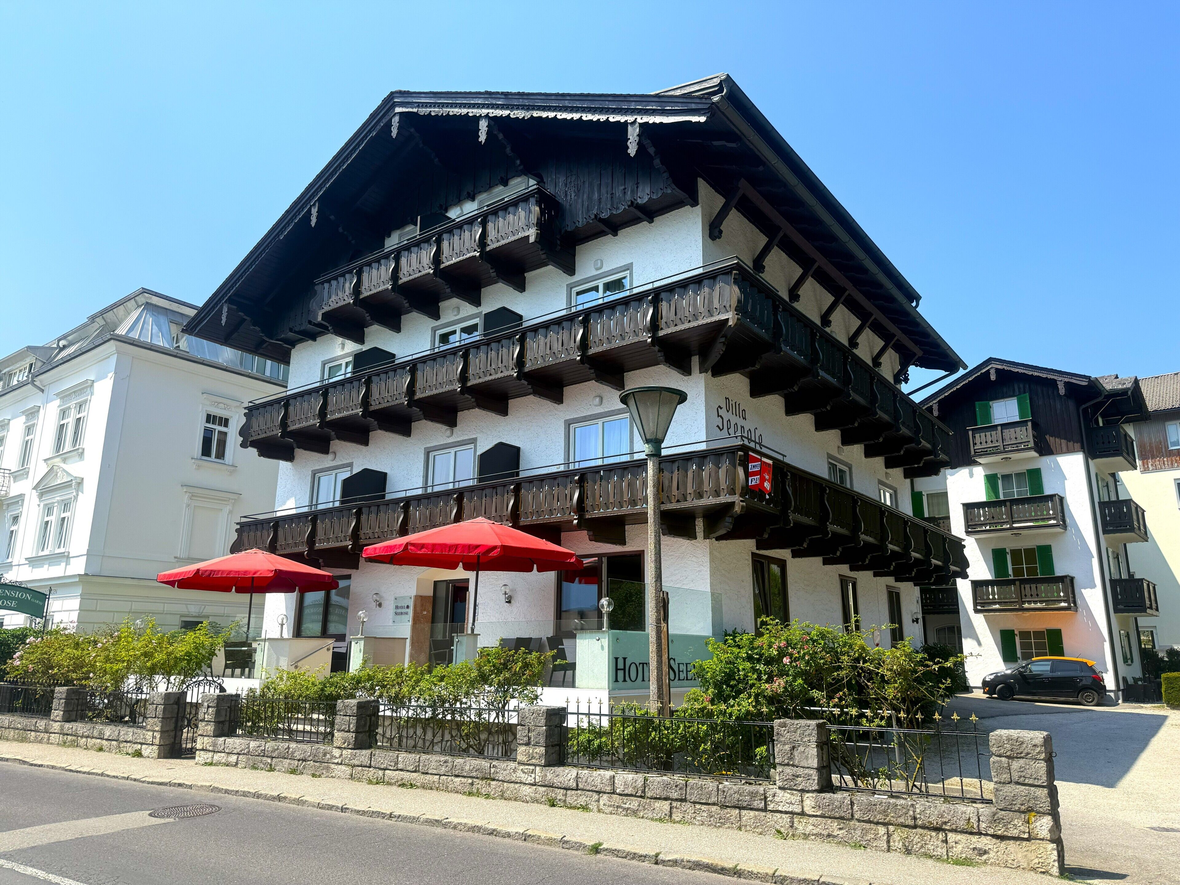A traditional building with multiple balconies, a sign indicating a hotel, and red umbrellas.