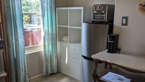 Una cocina compacta con refrigerador, cafetera y un mueble de madera.