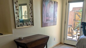 Una habitación con una mesa de madera, un espejo con detalles de mosaicos y un cuadro en la pared.