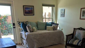 Un dormitorio con cama, una silla, una mesa y un ventanal.