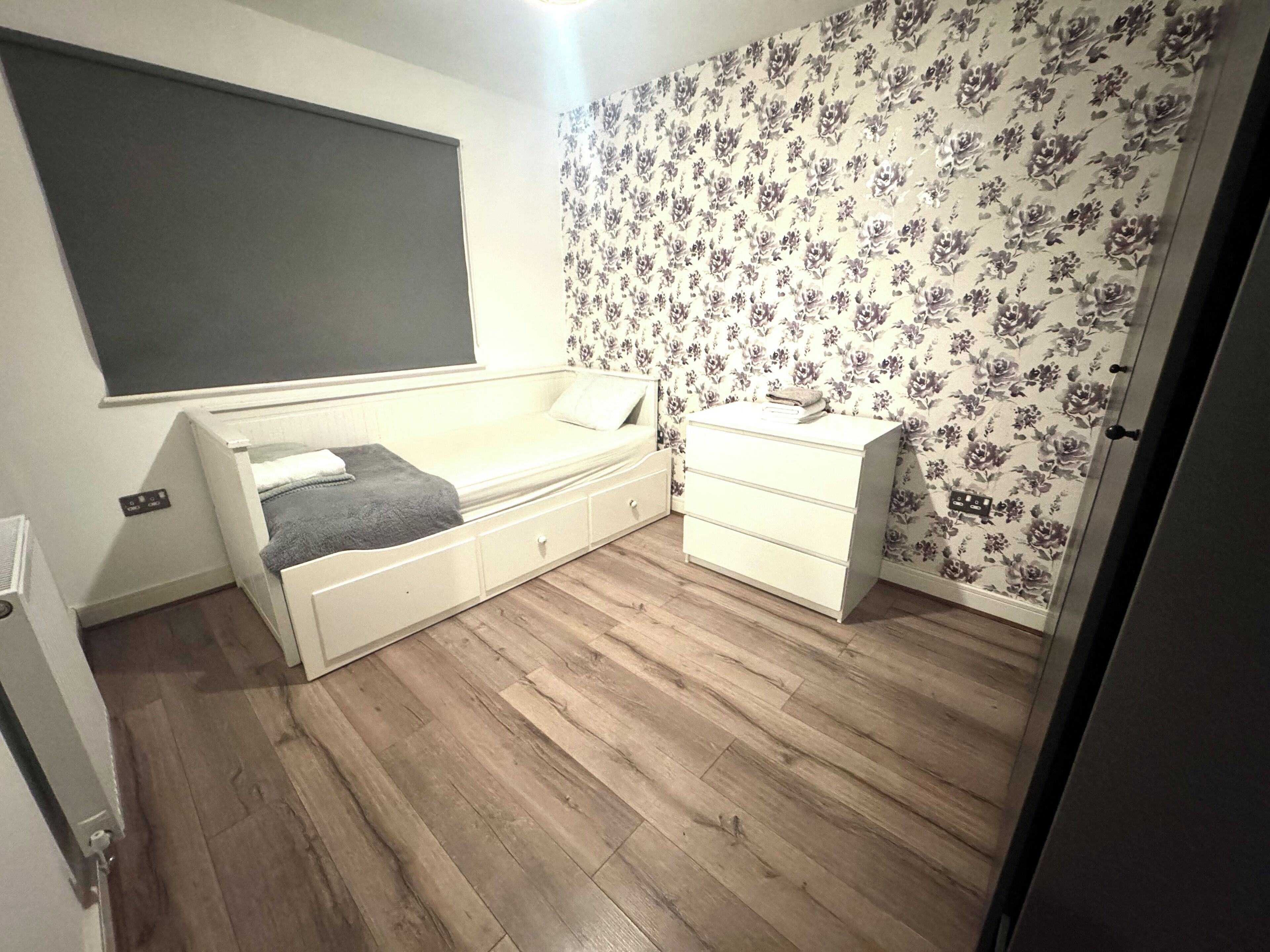Un dormitorio con cama, cómoda, escritorio pequeño y radiador.