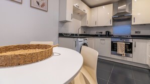 Una cocina moderna con armarios blancos, un horno de acero inoxidable y una lavadora.