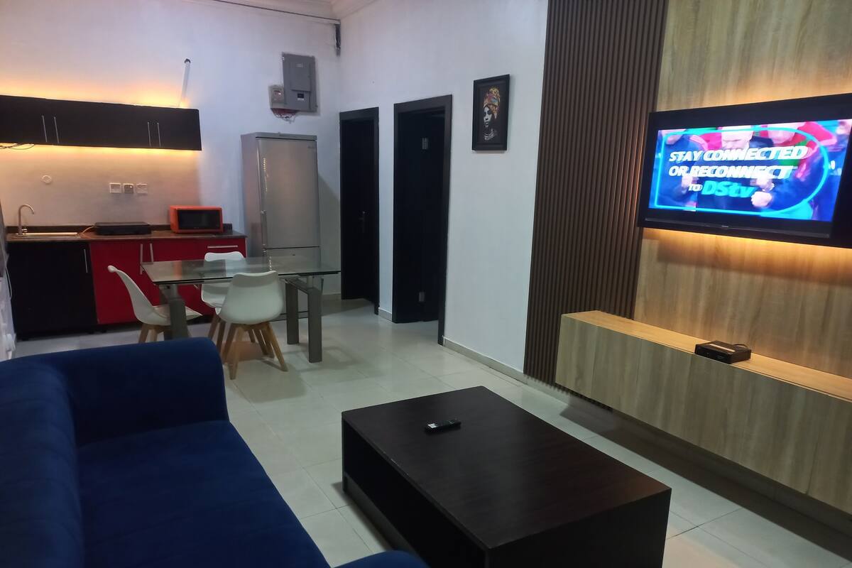 A modern living room with a sofa, coffee table, and a TV mounted on a wooden wall.
