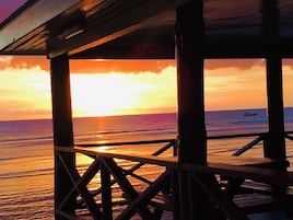 Un muelle de madera con vista a la puesta de sol sobre el océano.