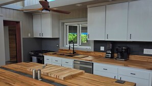 Una cocina moderna con una isla grande de madera, armarios blancos y una ventana que proporciona luz natural.