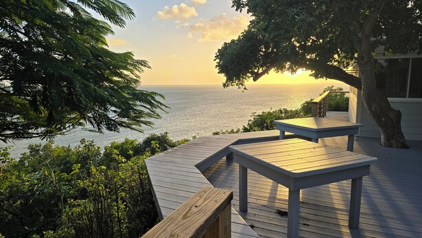 Terraza de madera con bancos que da a un cuerpo de agua al atardecer.