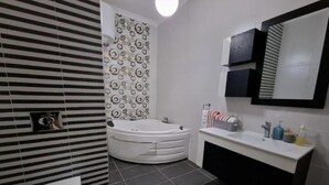 A modern bathroom with a toilet, a bathtub, and a vanity with a mirror. - Bugibba Central Modern Apartment, Charming 2-bedroom apartment with AC,  WiFi  (San Pawl il-Baħar)
