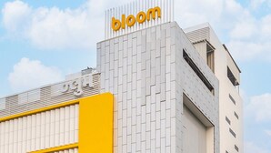 A building with a prominent 'bloom' sign on top, featuring a modern architectural design with a patterned facade and a yellow accent. - Bloom Hotel SG Highway (Ahmedabad)