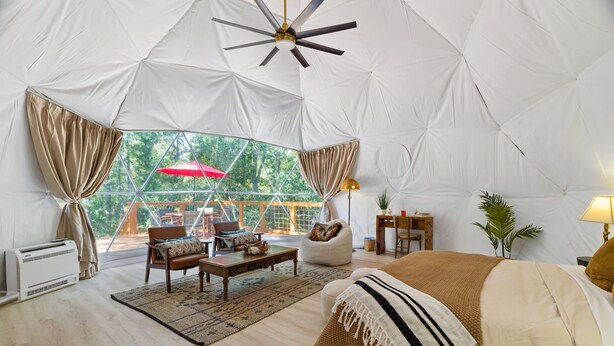 A spacious tented accommodation with a bed, seating area, and a view of the outdoors. - The Bird House | 6 Beds 2 Baths (Bastrop County)