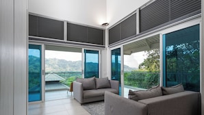 A modern living room with a large sliding glass door leading to a balcony with a mountain view. - Casa Maracuya (San Mateo)