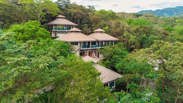 A multi-story building with a traditional architectural style, surrounded by dense forest. - Casa Maracuya (San Mateo)