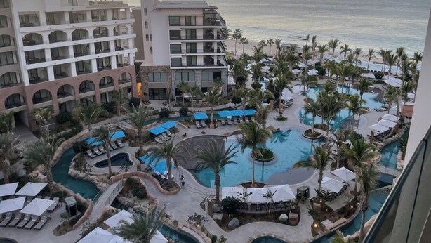 A resort with multiple swimming pools, palm trees, and a view of the ocean at sunset. - Luxury suite in serene San José del Cabo with AC, WiFi (San José del Cabo)