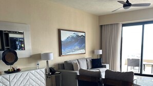 A modern living room with a glass dining table, two armchairs, a sofa, a ceiling fan, a large window with curtains, and a painting on the wall. - Luxury suite in serene San José del Cabo with AC, WiFi (San José del Cabo)