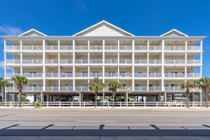 Un hôtel à plusieurs étages doté de balcons, d’un parking couvert et de palmiers.