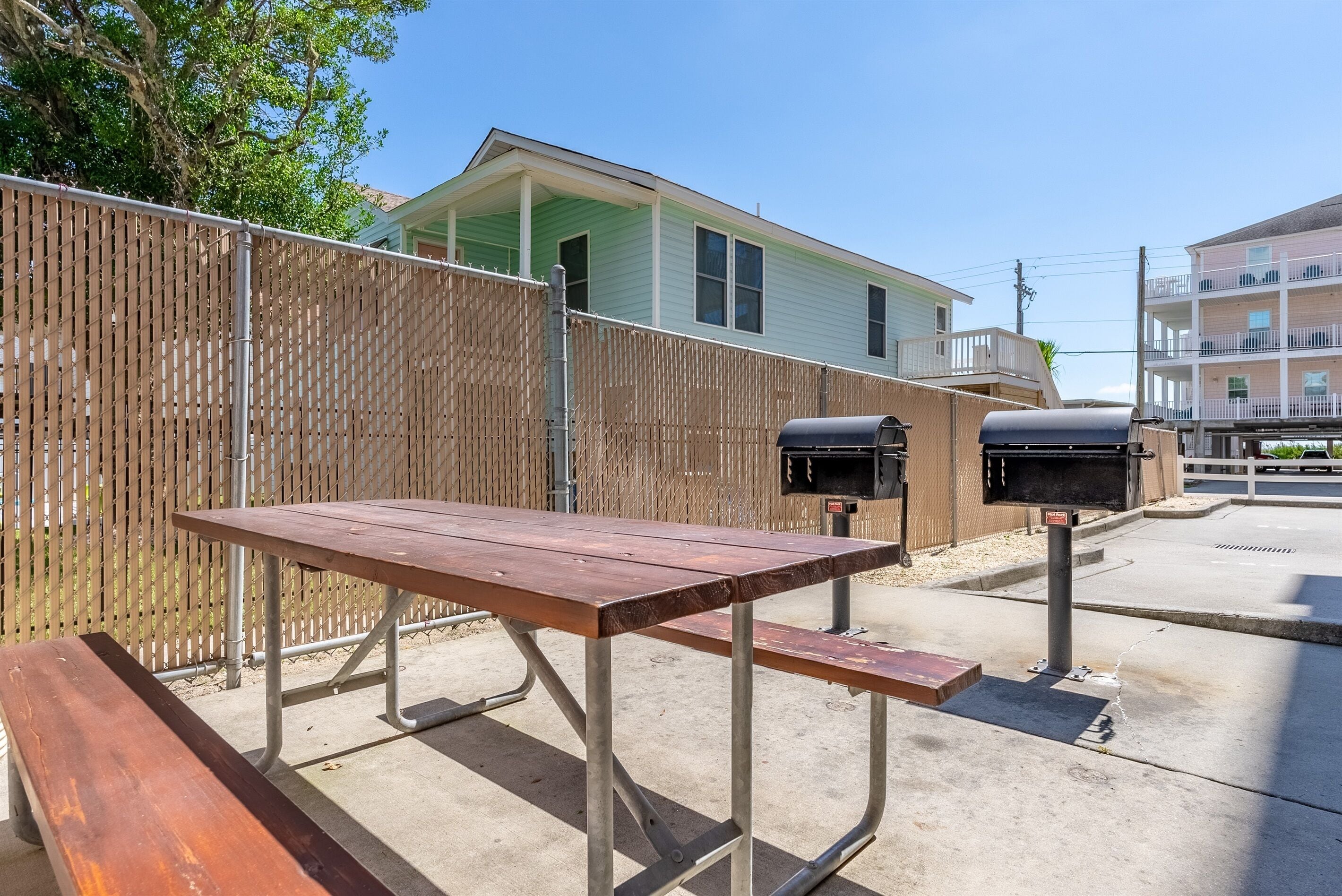 Une table de pique-nique avec un banc, une clôture en bois et une maison en arrière-plan.