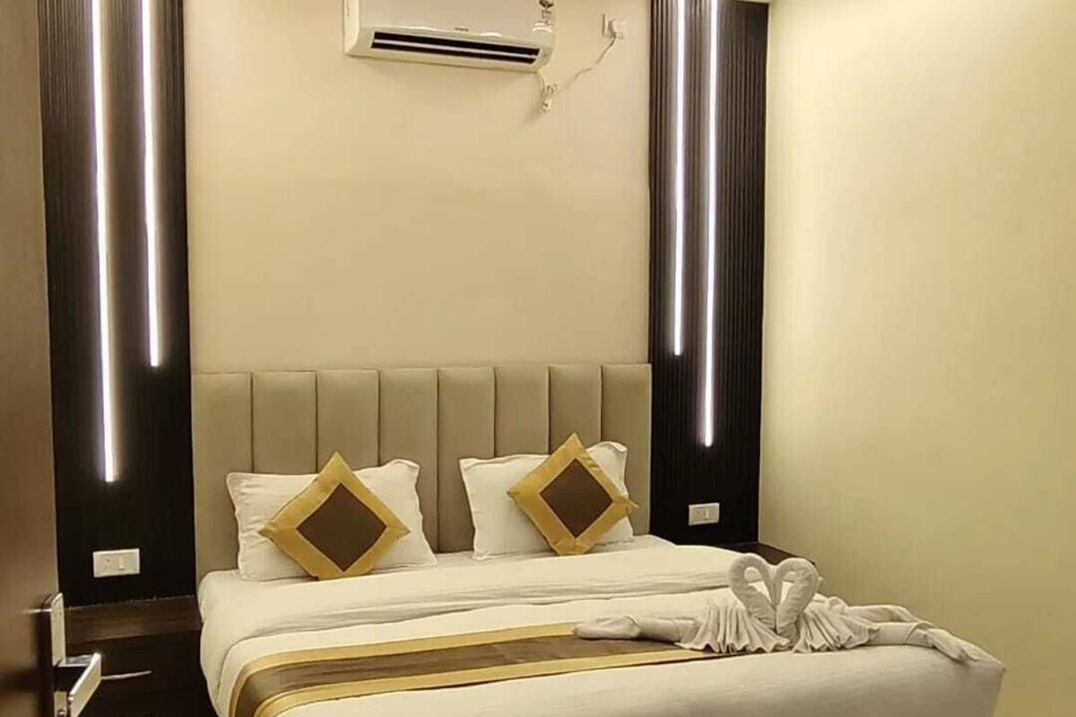 A hotel room with a large bed, a ceiling fan, an air conditioning unit, and a modern design.