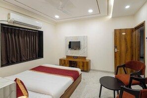Een hotelkamer met een bed, een aan de muur bevestigde televisie, een houten kast en een deur.