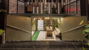 A staircase leading to a lounge area with a sofa and a small table, surrounded by plants and a decorative wall. - Hotel Money Plant (Chhatrapati Sambhajinagar)