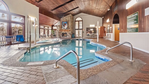 Une piscine intérieure avec un mur en pierre, un plafond en bois et un panneau indiquant les règles d’utilisation de la piscine.