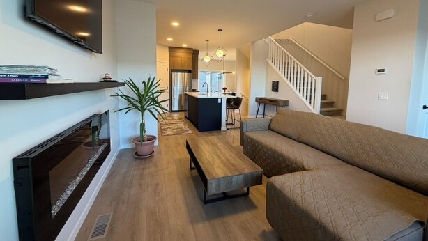 A living room with a fireplace, sofa, coffee table, and a TV mounted on the wall.