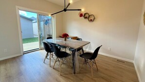 A dining area with a table and chairs, a pendant light, and a sliding glass door leading outside.