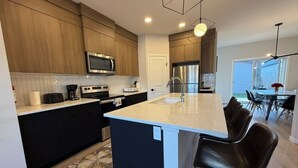 A modern kitchen with a central island, stainless steel appliances, and a dining area with a table and chairs.
