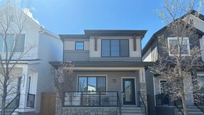 A modern two-story house with a stone foundation, a front porch, and a visible garage door.