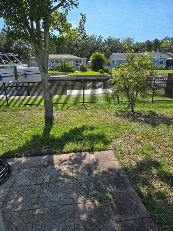 A residential area with a paved walkway, a small tree, and a metal fence. - Gulfside Getaway - Newly renovated waterfront 3-bedroom w/dock in Port Richey (Port Richey)
