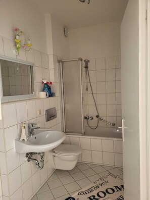 Modern bathroom with a sink, toilet, and shower enclosure, featuring a clean and functional layout.
