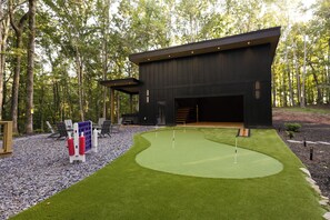 A modern building with a dark exterior, surrounded by a well-maintained lawn and trees.