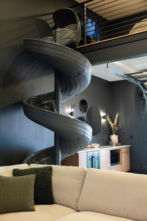 A modern interior with a spiral staircase, a sofa, and a decorative vase.