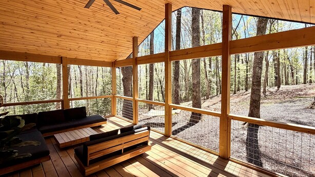 A wooden deck with a ceiling fan, a sofa, and a bench.