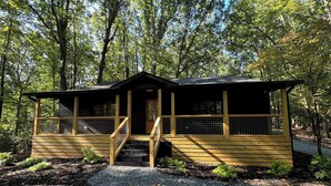 A cabin with a porch, a staircase, and a fenced deck area.