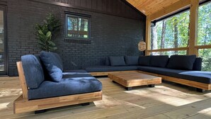 A modern interior with a dark brick wall, large windows, and wooden flooring.
