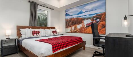 A bedroom with a bed, bedside tables, a desk, and a large window.