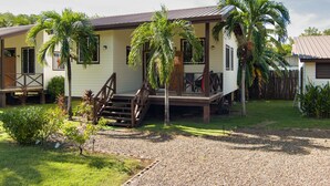 Ein zweistöckiges Haus mit Veranda, Palmen und einer Schotterauffahrt.