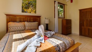 Ein Schlafzimmer mit Bett, Nachttisch, Lampe, Kleiderschrank und einem Bild an der Wand.