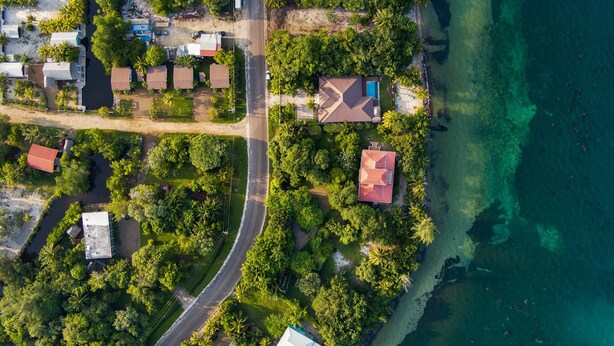 Vista aérea de una zona residencial costera con casas, una carretera y una playa.