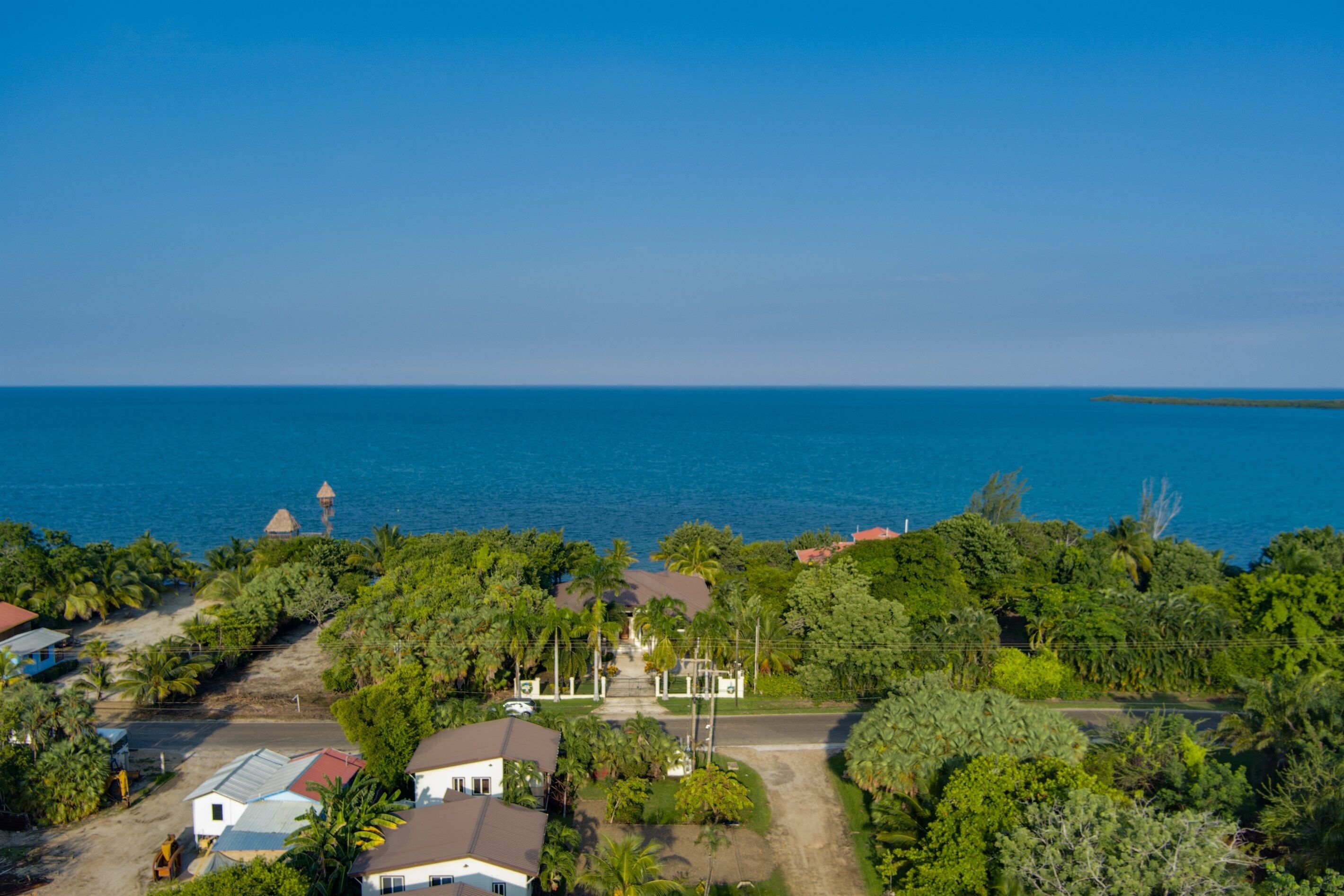 A coastal property with a central building surrounded by lush greenery and a view of the sea.