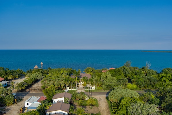 A coastal property with a central building surrounded by lush greenery and a view of the sea.