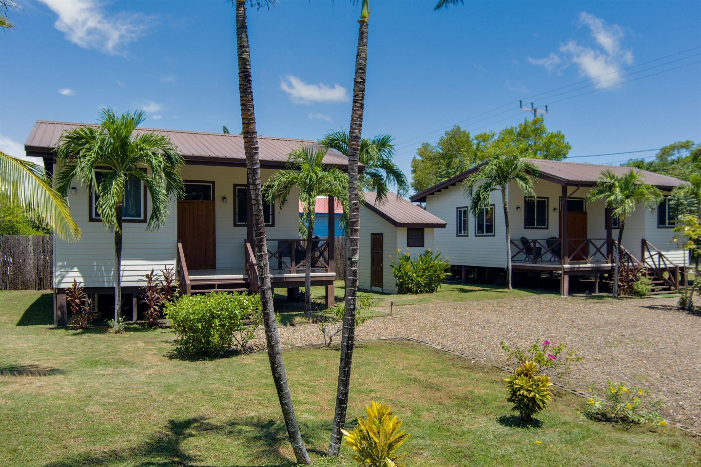 A two-story house with a porch, surrounded by palm trees and a well-maintained lawn.